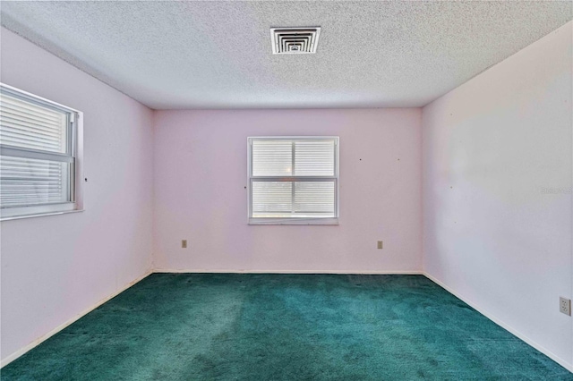 unfurnished room featuring a textured ceiling and dark colored carpet