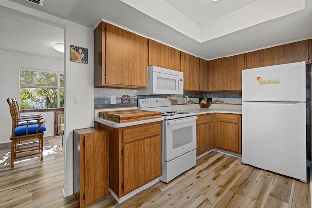 kitchen with white appliances, light hardwood / wood-style floors, and backsplash