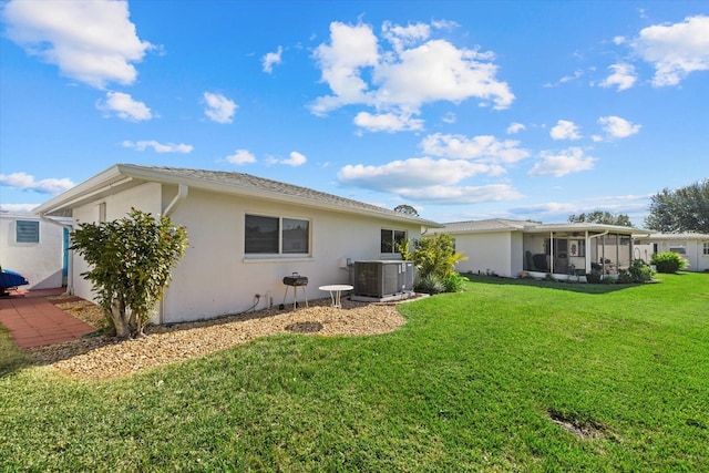 rear view of property with a sunroom, cooling unit, and a yard