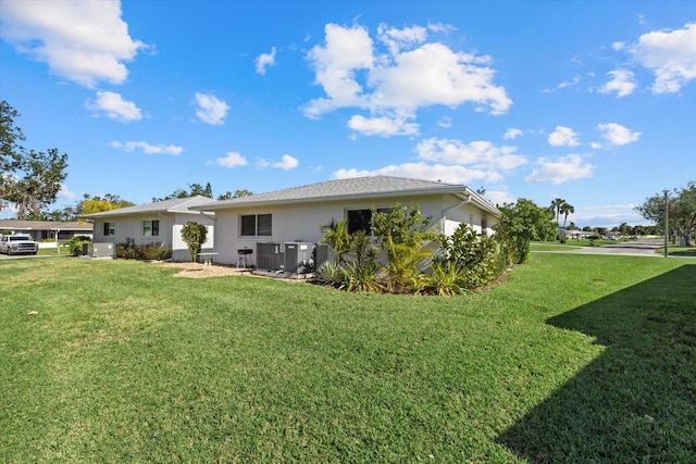 rear view of property featuring a yard and central AC