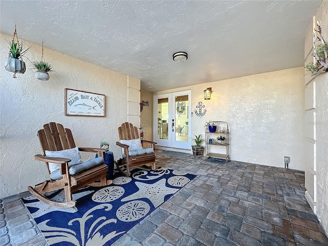 living area with french doors and a textured ceiling