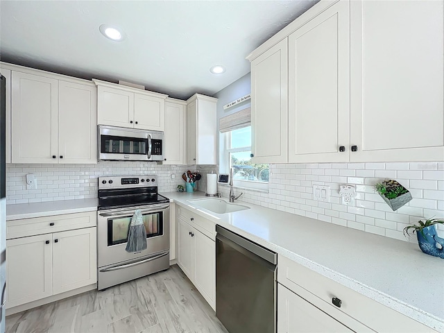 kitchen featuring decorative backsplash, light wood-type flooring, white cabinetry, and appliances with stainless steel finishes