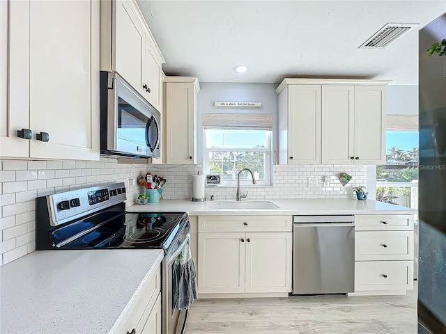 kitchen featuring light wood-type flooring, stainless steel appliances, tasteful backsplash, and sink