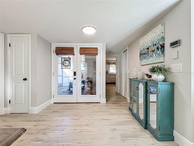 entryway featuring french doors, light wood-type flooring, and a wealth of natural light