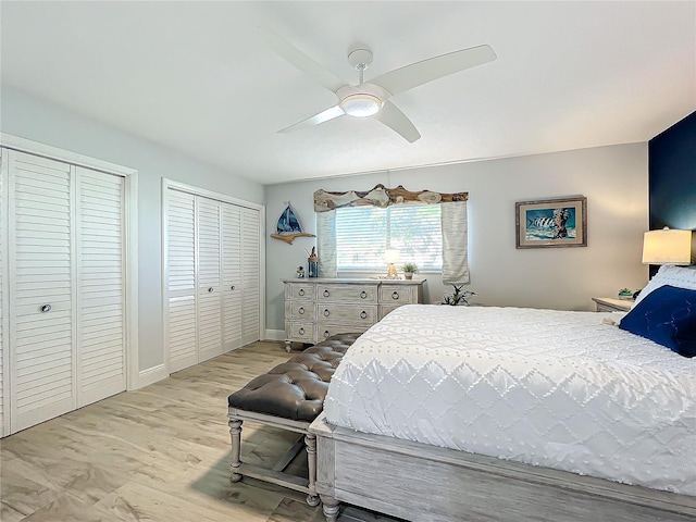 bedroom featuring ceiling fan, light wood-type flooring, and multiple closets