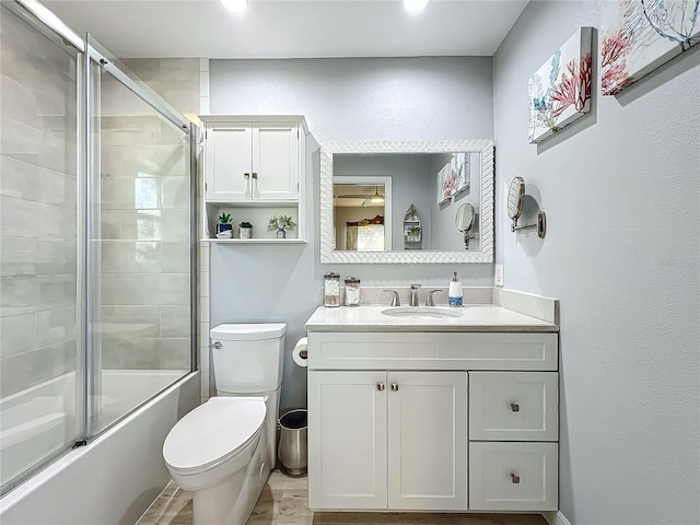 full bathroom featuring vanity, enclosed tub / shower combo, and toilet