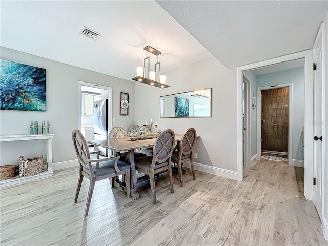 dining space featuring a notable chandelier and light wood-type flooring