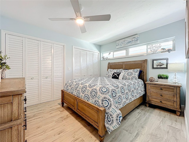 bedroom featuring ceiling fan, two closets, and light hardwood / wood-style flooring