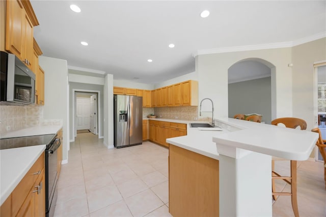 kitchen with sink, a breakfast bar area, ornamental molding, appliances with stainless steel finishes, and kitchen peninsula