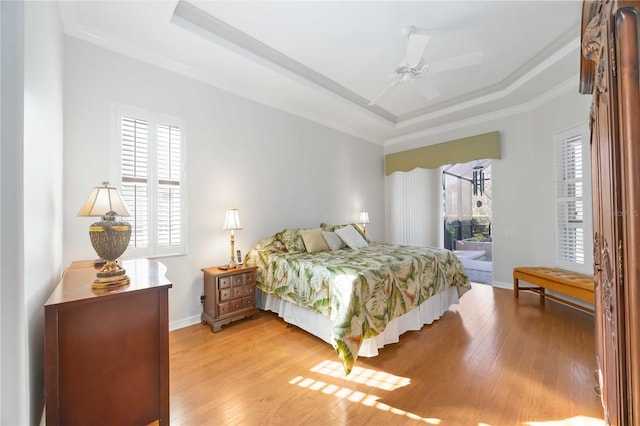 bedroom featuring access to exterior, a raised ceiling, and light hardwood / wood-style floors