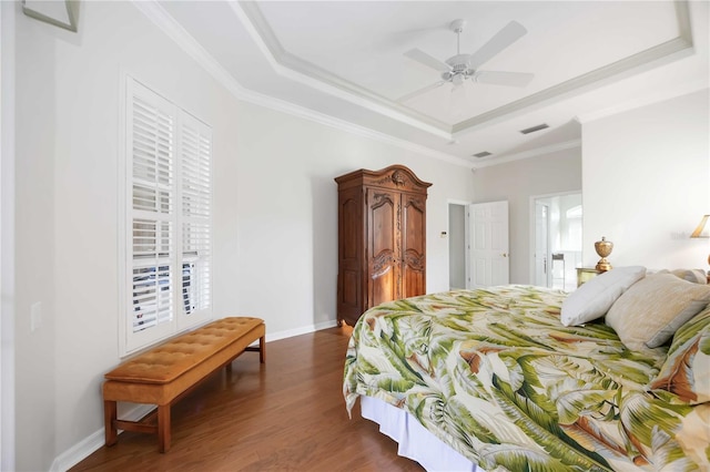 bedroom featuring dark hardwood / wood-style floors, ornamental molding, a raised ceiling, and ceiling fan