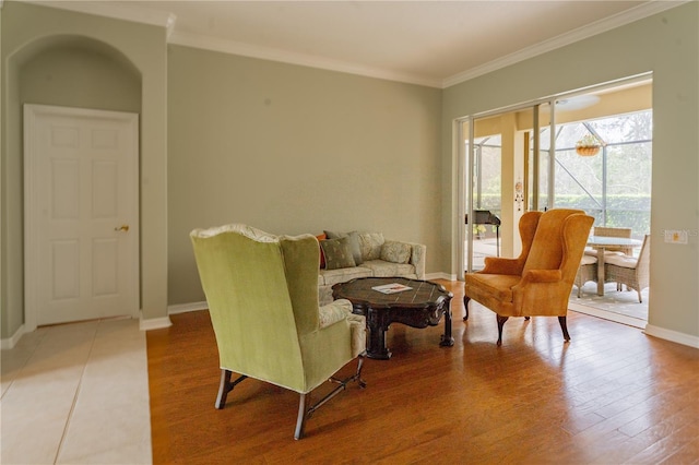 sitting room featuring baseboards, crown molding, and wood finished floors