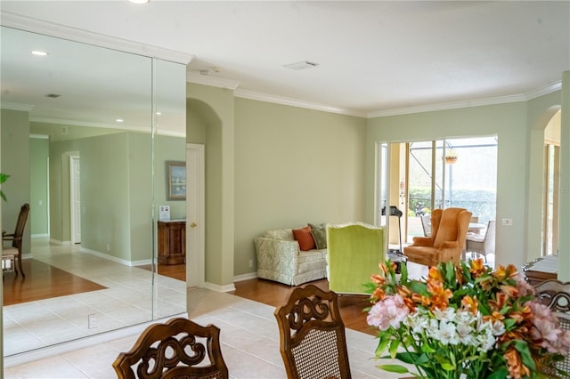 living area with arched walkways, ornamental molding, light tile patterned floors, and baseboards