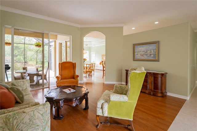 living area featuring baseboards, arched walkways, ornamental molding, wood finished floors, and recessed lighting