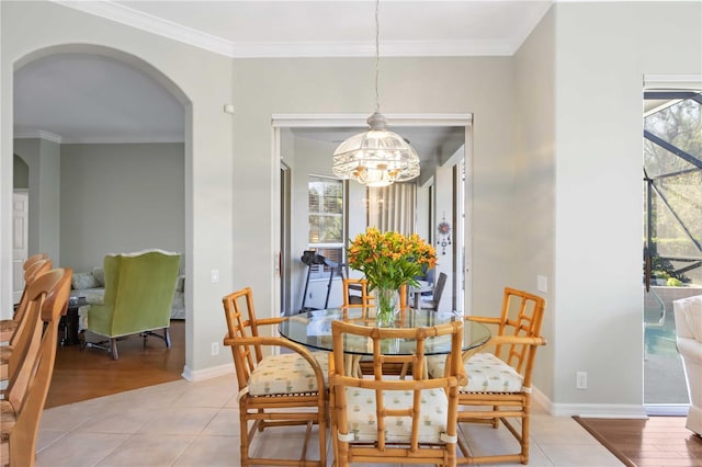 dining area with arched walkways, crown molding, baseboards, and light tile patterned floors