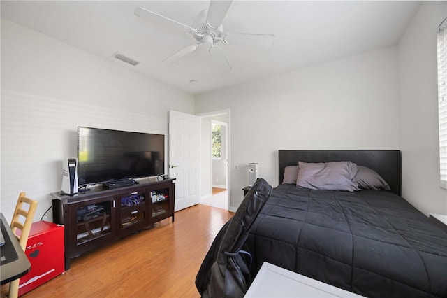 bedroom with a ceiling fan, visible vents, and wood finished floors