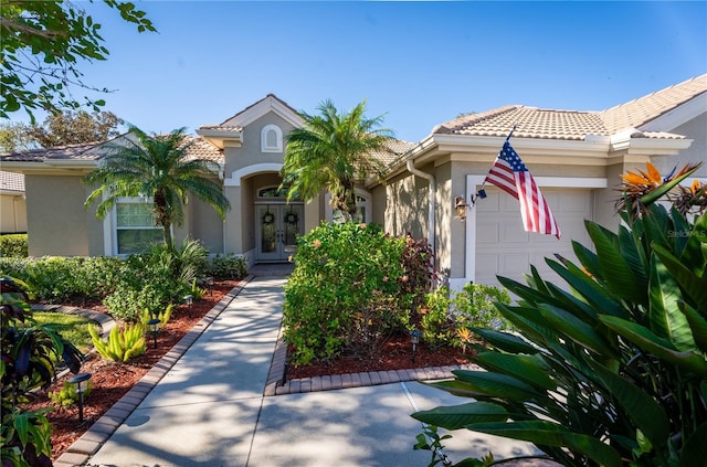 mediterranean / spanish-style house with french doors, a tile roof, an attached garage, and stucco siding