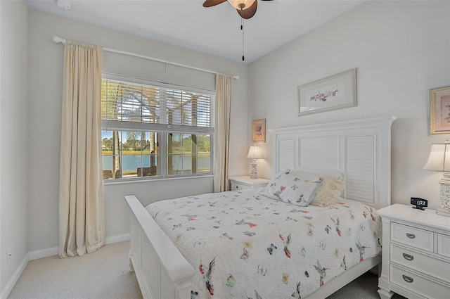 bedroom with ceiling fan, a water view, and light carpet