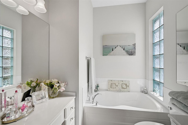 bathroom featuring vanity, a healthy amount of sunlight, and a tub