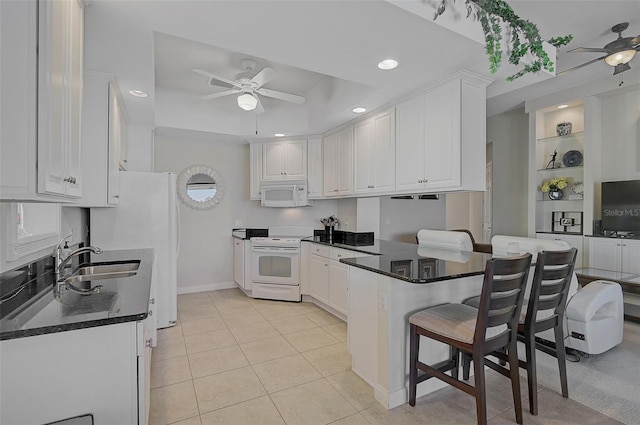 kitchen featuring white cabinetry, sink, kitchen peninsula, white appliances, and a breakfast bar