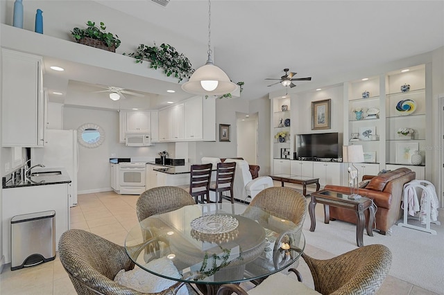 tiled dining space featuring built in shelves, ceiling fan, and sink