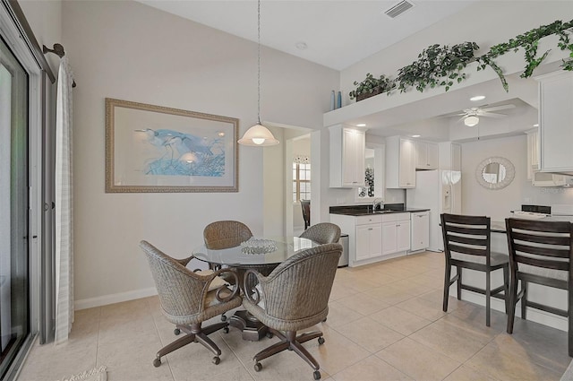 tiled dining space featuring ceiling fan, sink, and a high ceiling