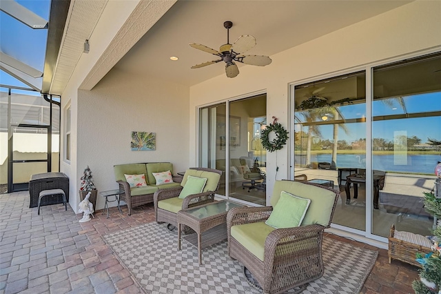 view of patio featuring a lanai, ceiling fan, and a water view