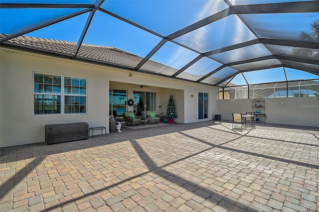 back of property featuring glass enclosure, ceiling fan, and a patio area