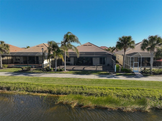 back of property featuring glass enclosure, a water view, and a yard