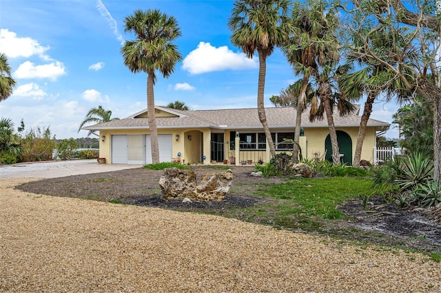 single story home featuring a garage, driveway, fence, and stucco siding