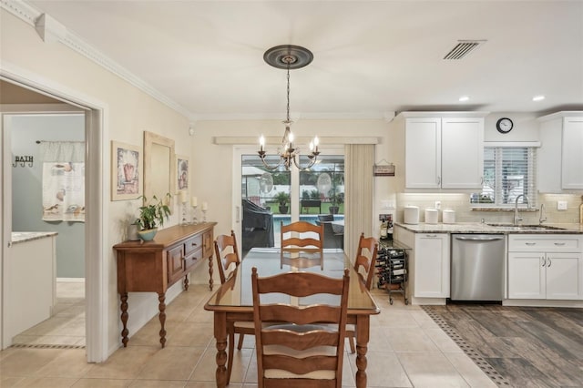 tiled dining area featuring a notable chandelier, crown molding, and sink