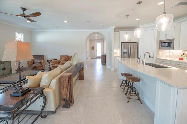 kitchen featuring white cabinetry, sink, pendant lighting, a breakfast bar, and appliances with stainless steel finishes