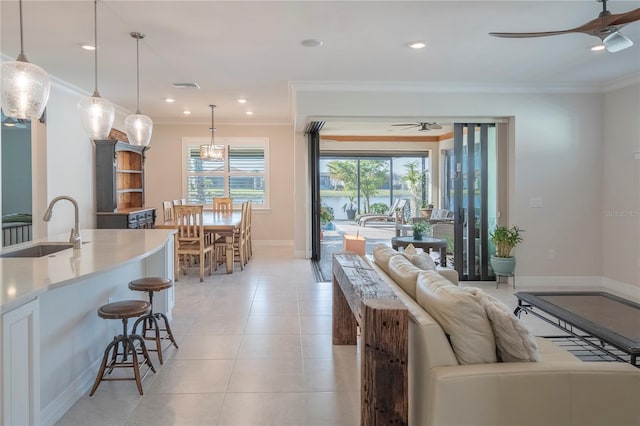 living room featuring light tile patterned floors, ceiling fan, crown molding, and sink