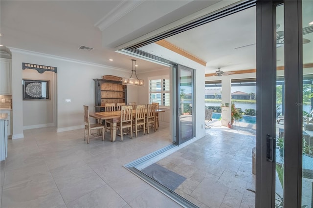 dining space with crown molding, a water view, and ceiling fan with notable chandelier