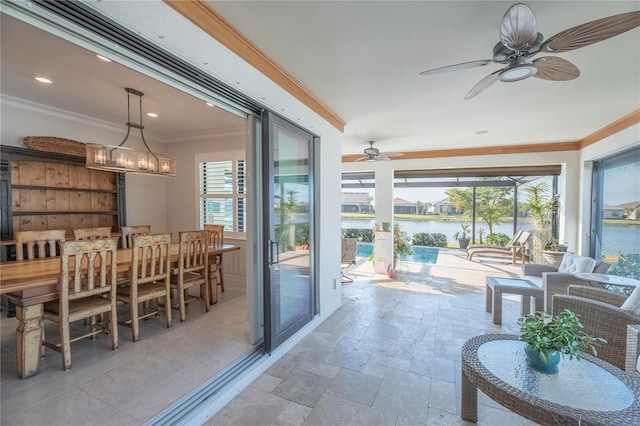 sunroom / solarium with ceiling fan with notable chandelier, a water view, and a wealth of natural light