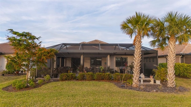 back of house with glass enclosure and a yard