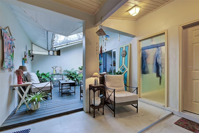 sitting room featuring concrete flooring, lofted ceiling with beams, and wood ceiling