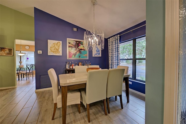 dining room featuring baseboards, visible vents, wood finished floors, an inviting chandelier, and high vaulted ceiling