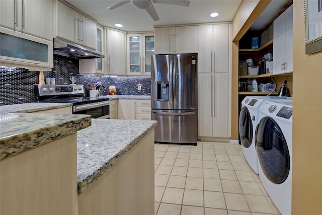 kitchen with light tile patterned floors, stainless steel appliances, backsplash, washing machine and dryer, and under cabinet range hood