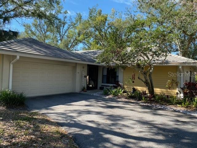 ranch-style house with aphalt driveway and an attached garage