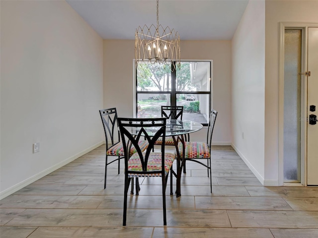 dining space featuring light wood-style floors, a notable chandelier, and baseboards