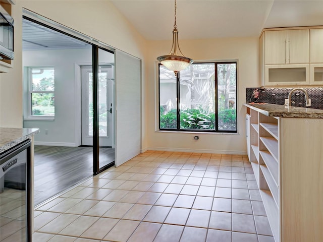 unfurnished dining area featuring lofted ceiling, beverage cooler, baseboards, and a sink