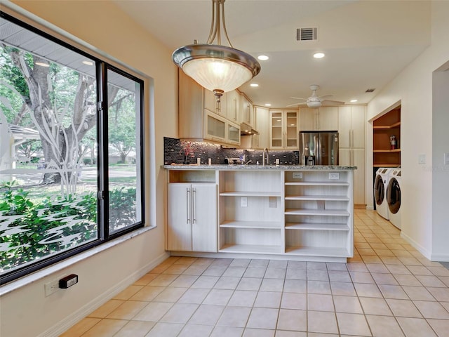 kitchen with a wealth of natural light, open shelves, washer and clothes dryer, and stainless steel fridge