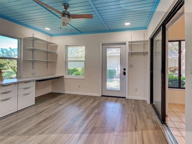unfurnished office featuring built in desk, ceiling fan, light wood-style flooring, baseboards, and wood ceiling