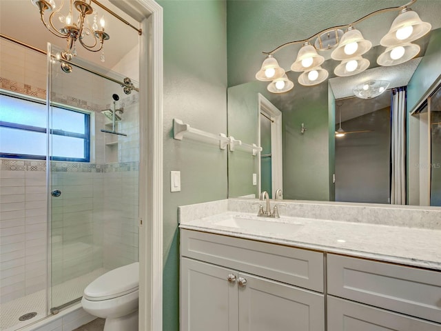 bathroom with an inviting chandelier, vanity, toilet, and a stall shower