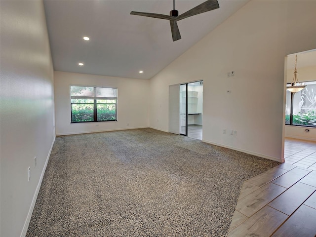 empty room with a ceiling fan, high vaulted ceiling, a wealth of natural light, and baseboards