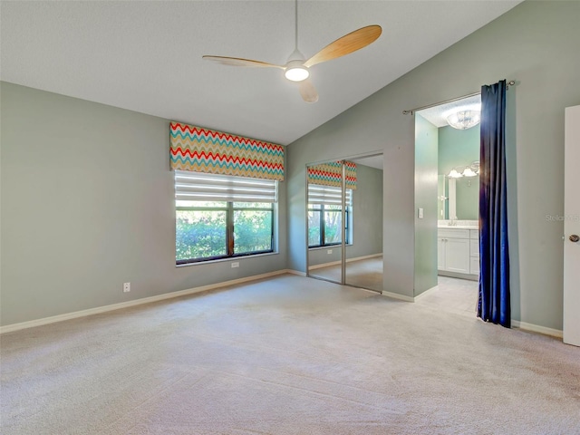 unfurnished bedroom with carpet floors, a closet, vaulted ceiling, baseboards, and a ceiling fan