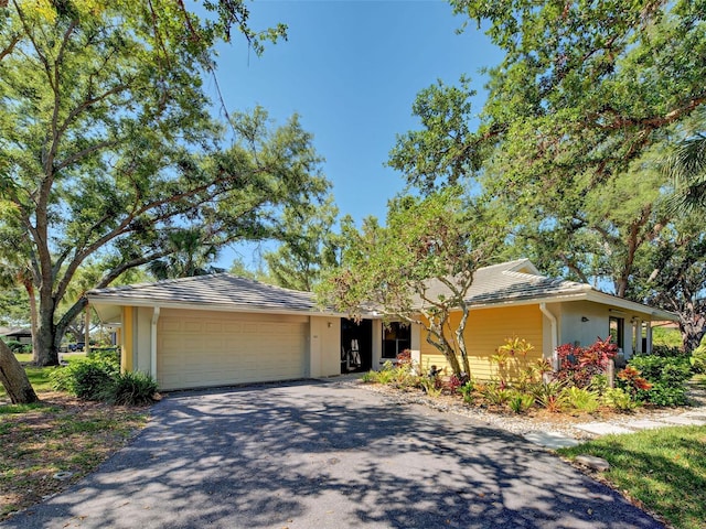 ranch-style house with stucco siding, an attached garage, and aphalt driveway