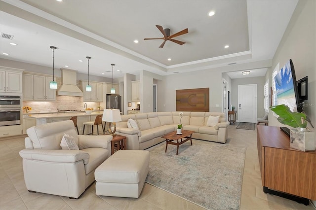 tiled living room featuring a tray ceiling and ceiling fan