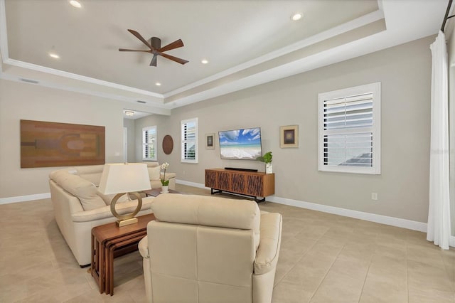 tiled living room with ceiling fan, a raised ceiling, and crown molding